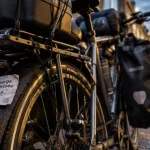 Mauvais montage portes bagages vélo : sacoches ballottent, vélo sur trottoir humide